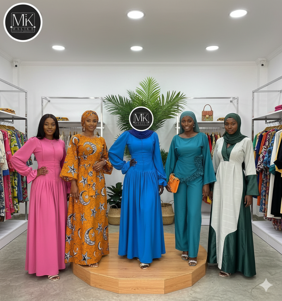 Une boutique de vêtements bien organisée, avec des portants de vêtements variés de chaque côté, présentant un mélange de couleurs et de styles. L'espace est baigné de lumière avec des murs blancs et un design minimaliste, tandis qu'une plante en pot apporte une touche de verdure.